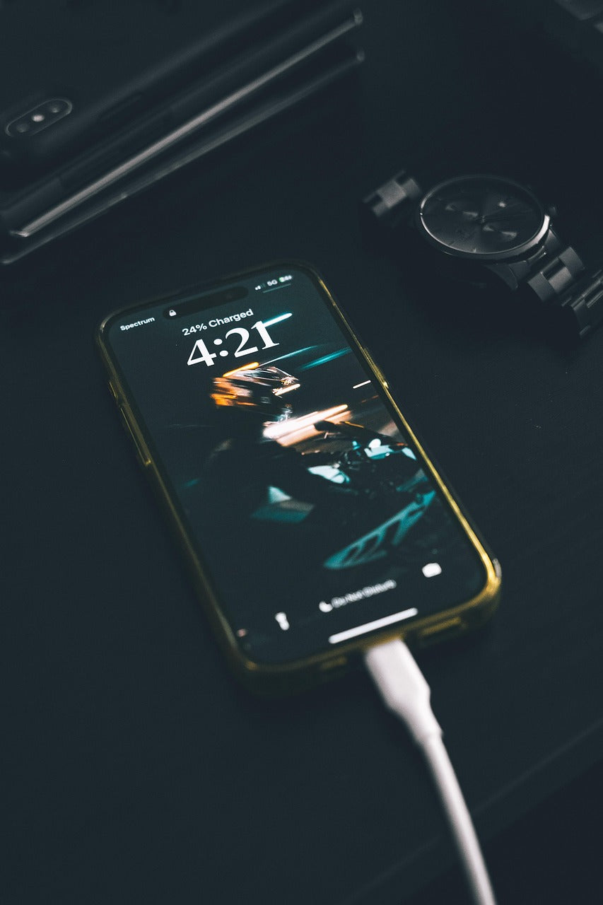 Smartphone charging with text overlay: 'Muse Mile, we offer premium unlocked iPhones, Samsung & Motorola, fast shipping, great prices.'